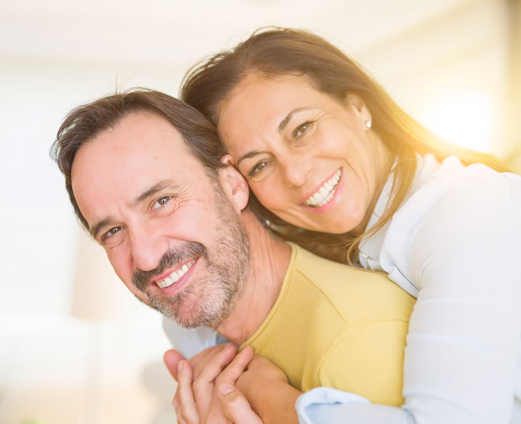 A happy couple hugging and smiling at Aesthetic Periodontal & Implant Specialists 